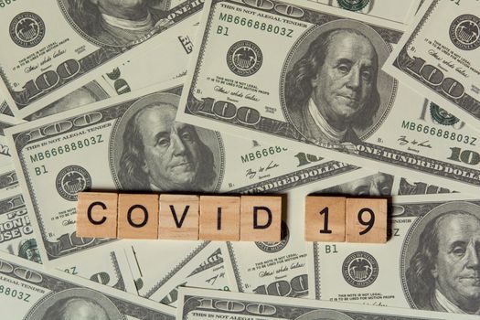 COVID-19 coronavirus with wooden alphabet blocks, on 100 dollar money background with copy space

