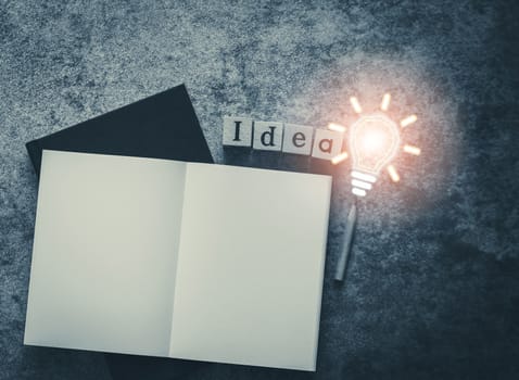 Cube letter word of Idea with notebook, sharp pencil and bulb light with copy space. Futuristic icon photo concept of business and education, thinking and problem solving, creativity invention.