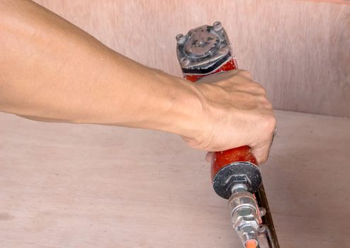 Hands of artisan furniture with an air gun to shoot for the wood.