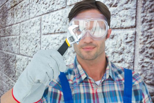 Plumber holding adjustable wrench against grey brick wall