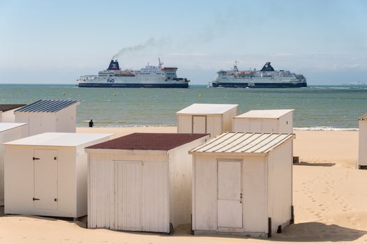 Calais, France - 19 June 2018: Beach cabins and DFDS / P&O cross Channel ferries.