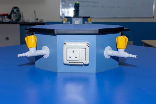Two Science laboratory gas nozzles and electricity on a blue empty school lab table in an educational setting for experiements, analysis and research