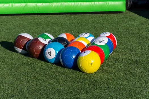 Vibrant billiards soccer/footballs balls on the green grass cued up for children's recreation and fun outdoors.