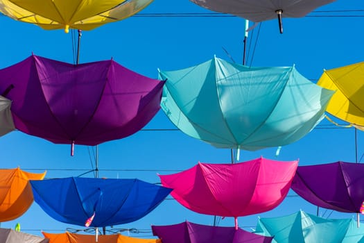 Colorful vibrant umbrellas hanging over the walking street for a festival on a blue sky sunny day.