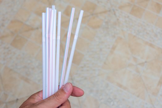 Hand holding household plastic straws symbolizing plastic pollution global problems and need for environmental change.
