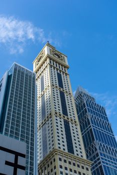 "Dubai, Dubai/United Arab Emirates - 1/25/2020: Dubai International Financial Centre (DIFC)  Iconic The Tower (clock) amid modern Dubai skyscrapers on blue sky."
