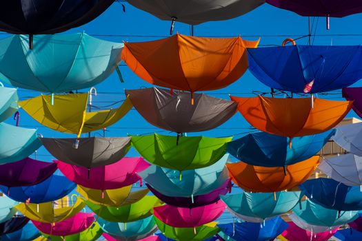 Colorful vibrant umbrellas hanging over the walking street for a festival on a blue sky sunny day close up