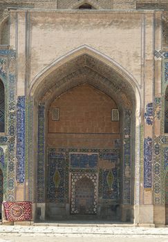 Arch and door with peeling traditional ancient Asian mosaic. the details of the architecture of medieval Central Asia