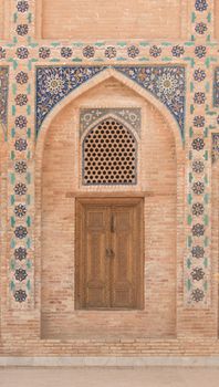 Wooden door with ancient traditional Asian ornamentation and mosaics. the details of the architecture of medieval Central Asia
