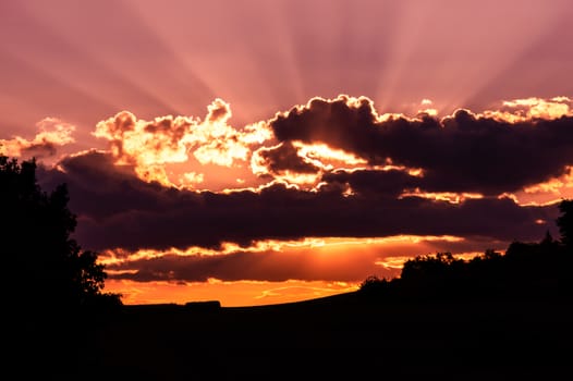 colorful sunset with clouds and black horizon