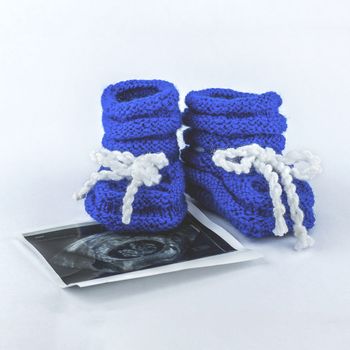It is a boy. Pregnancy. Waiting for a baby. Blue slippers with a photo of ultrasound on a white background.