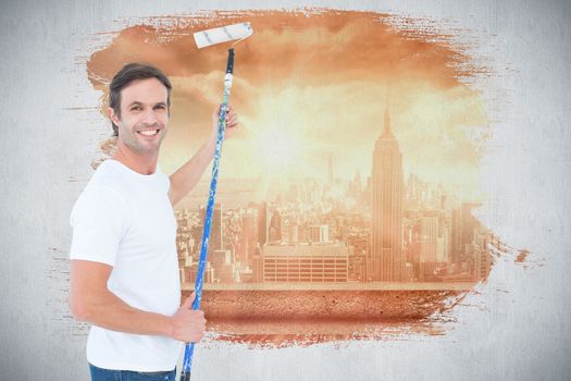 Happy man using paint roller against sun shining over city