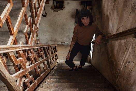 Portrait of a brunette girl in a staircase of an abandoned House, image in low light