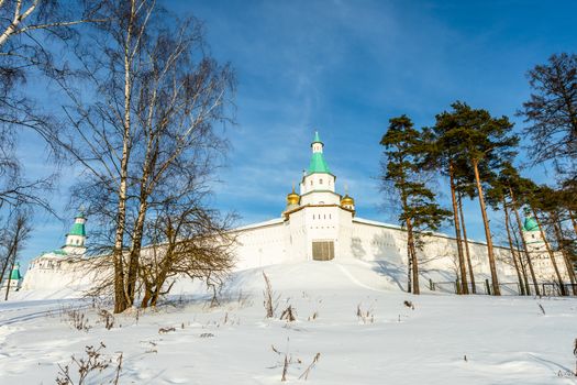 Snow and white walls, golden domes and a tower gate of New Jerusalem Monastery, Istra, Moscow region, Russia