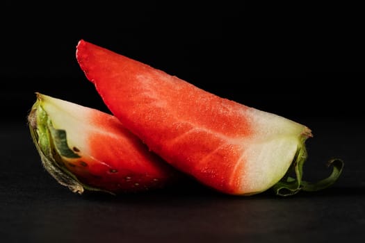 Two pieces of red strawberries on a black background.