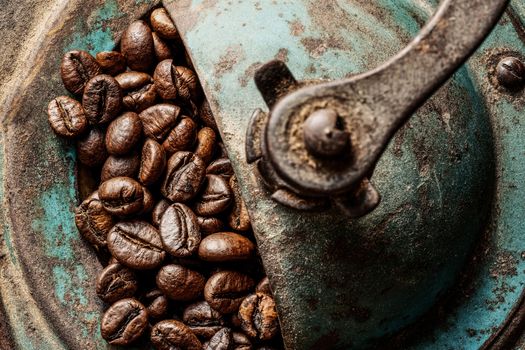 Old blue coffee grinder with coffee beans. Top view, detail.