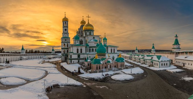 Sunset lights over Voskresensky cathedral golden domes, covered in snow, Resurrection or New Jerusalem Monastery, Istra, Moscow region