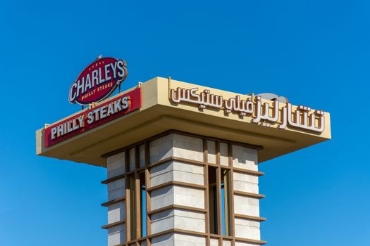 Charley's Philly Steaks sign on a blue sky background in the Middle East in the United Arab Emirates in English and Arabic.