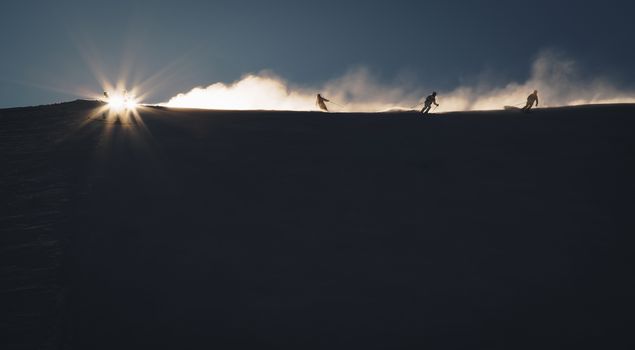 Skiers enjoying an early morning in slopes at the Austrian Alps with a nice sunshine backlight