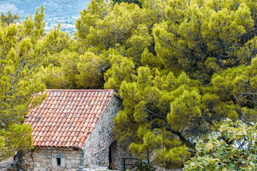 Mediterranean architecture. The roof of the building, covered with red tiles, among the greenery.