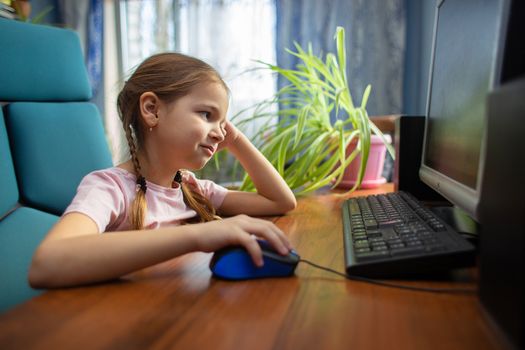 Tired girl schoolgirl is engaged at home on the computer. A child in distance learning. Computer games