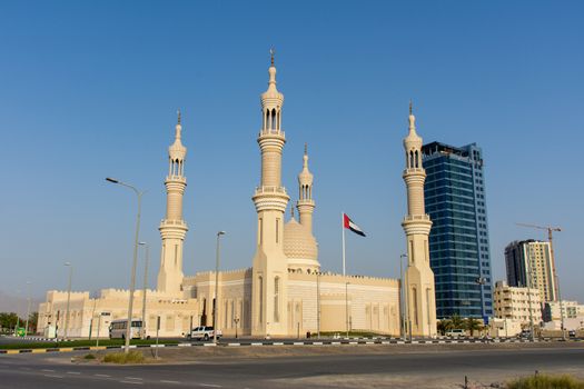 "RAK, RAK/UAE - 5/6/2019: Late afternoon at the Sheikh`s Zayed`s Mosque in Ras al Khaimah, UAE; stands out on the Corniche. Flag flying in the background on a quiet Ramadan afternoon."