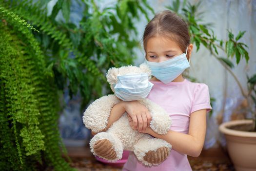 The girl put on a medical mask on herself and on her teddy bear. Quarantine