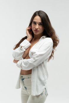 young beautiful girl pose in a white shirt and white jeans in the studio