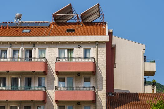 Hotel building, windows, balconies and solar panels on the roof, fragment.