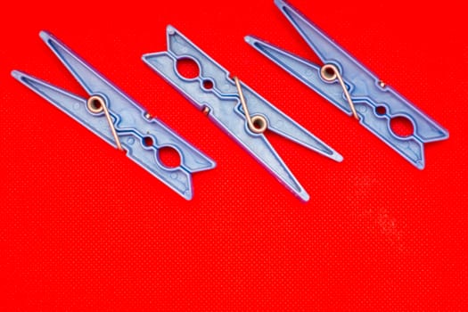 Blue clothes pins on red background concept (left side). Open space.