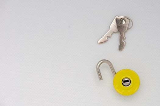 Silver keys and a yellow unlocked padlock on an isolated white background. Freedom and escape.