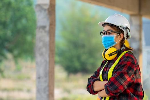 Female engineer wearing protective mask to Protect Against Covid-19 with helmet safety in the construction site,Coronavirus Protective, safety concept.