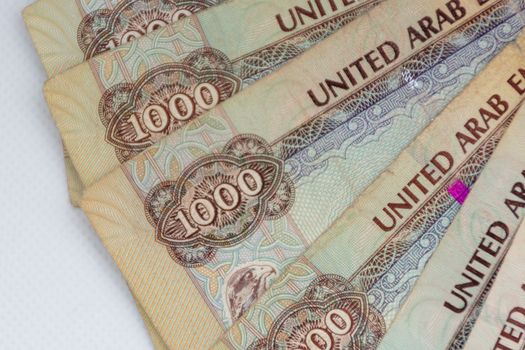 The Currency of the United Arab Emirates (UAE) - Thousand Dirham notes spread out on a white background. Money exchange.