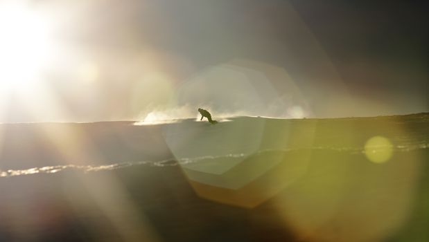 Snowboarder enjoying an early morning in slopes at the Austrian Alps with a nice sunshine flare