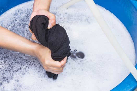 Female hands wash clothing by hand with detergent in basin. selective focus and space for text.