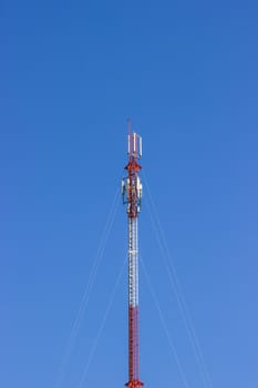 Red and white Telecommunication tower in a day of clear blue sky. Telephone pole