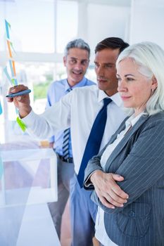 Businessman writing on post it with his colleagues in office 