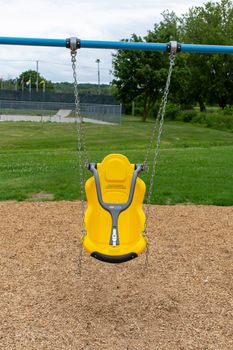 "Brighton, Ontario/Canada - 07/22/2019: Little tikes yellow disability swing for handicapped or special needs children at a park."