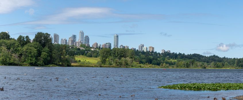 Panorama of Burnaby, British Columbia, Canada skyline from Deer Lake looking towards Metrotown and apartment complexes on a sunny summer day.