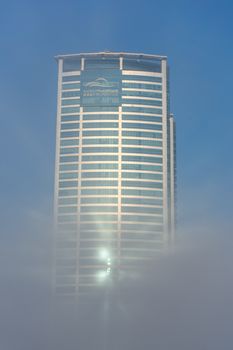 "RAK, RAK/UAE - 10/5/2018 Ras Al Khaimah City in the United Arab Emirates in the early morning fog. Julphur Towers, RAK Properties, peeks above the clouds into the blue sky."