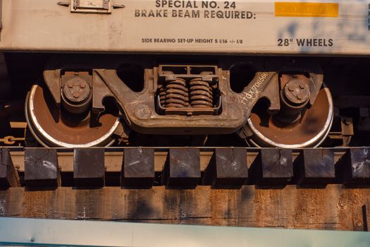 Close up of train wheels and break system in motion on track on wooden train bridge."