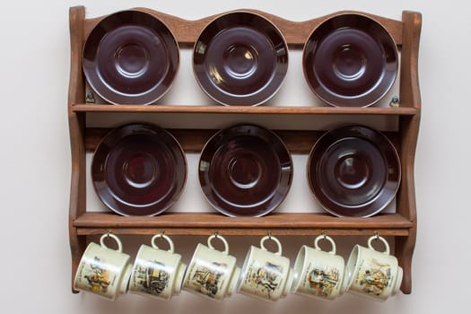 Dutch mugs and plates hanging on a rustic wooden frame on the wall. Culture of Holland in the Netherlands. Common in homes.