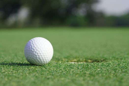 Close-up on a golf ball on a green grass near the hole