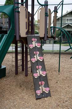 Outdoor wall climbing grips and wall going up the playground structure. Exercise, fitness, problem solving and fun.