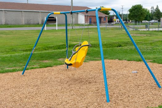 "Brighton, Ontario/Canada - 07/22/2019: Little tikes yellow disability swing for handicapped or special needs children at a park."