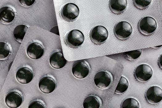 raw green compact spirulina powder pills in medical blister packs close-up with selective focus and background blur