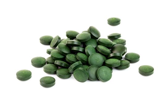 a small pile of green spirulina pills isolated on white background in near above perspective