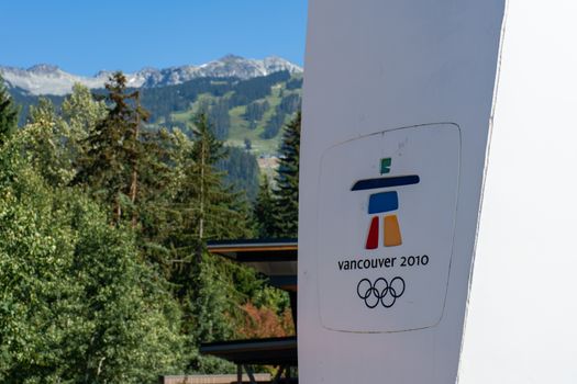 "Whistler, British Columbia/Canada - 08/07/2019: Whistler village Vancouver 2010 Olympics sign looking towards the Whistler Mountain and Blackcomb ski resort and logo for games the inukshuk"