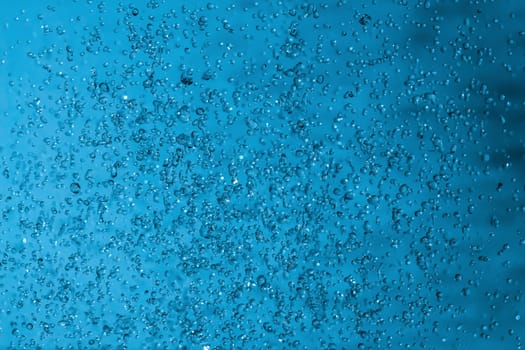 Water splashes on blue background. Spray. Drops of water on the glass window. Rain, shower. sprinkle a little, pour