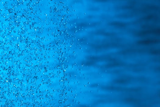 Water splashes on blue background. Spray. Drops of water on the glass window. Rain, shower. sprinkle a little, pour